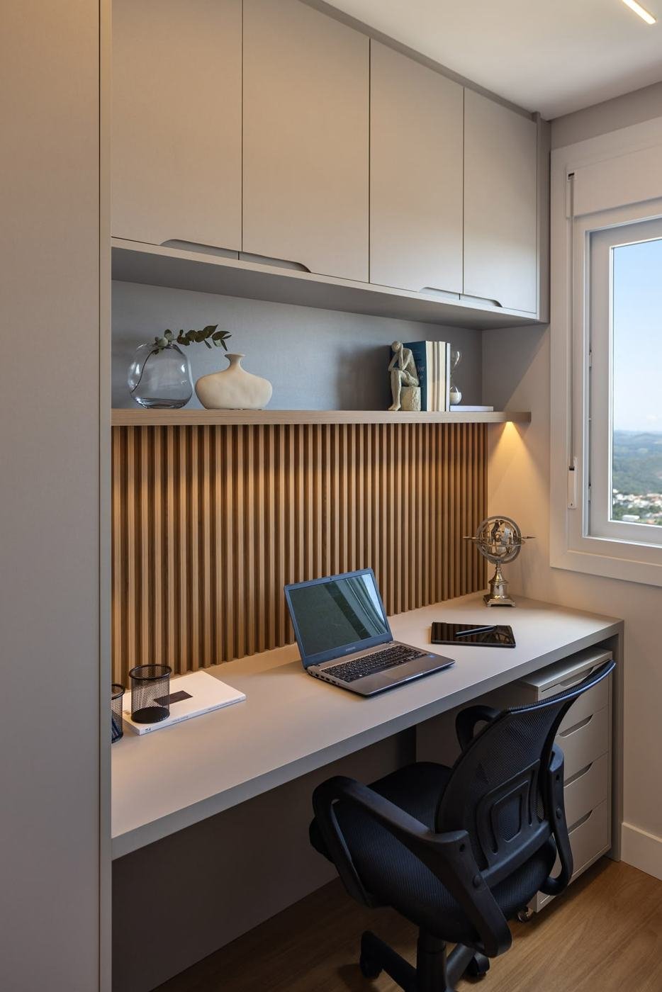 Home office com bancada, armários aéreos e painel ripado